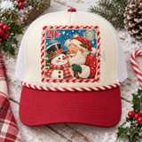 Vintage-style Christmas postage stamp DTF transfer featuring Santa Claus nuzzling noses with a plaid-scarved snowman under a starry night sky, framed by a candy-cane striped stamp border Shown on a cream front panel / cardinal red bill / white mesh back with a red-and-white twisted rope trucker hat.
