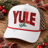 Yule-ish Christmas DTF transfer with mixed buffalo plaid, leopard print, distressed, and checkerboard pattern lettering and dark green brush-script ish. text Shown on a white front panel with red rope and leopard mesh back trucker hat.