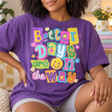 Better Days Are On The Way DTF transfer with colorful paper-collage lettering, a smiley face, stars and flowers Shown on a Grape t-shirt.