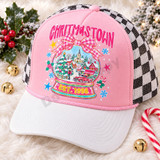 Christmas Town snow globe DTF transfer with pink gingham bow, candy stripes, snowy village scene, red pickup truck, and Est. 1998 banner Shown on a Blossom pink front panel with white bill and black-and-white checkered mesh back trucker hat.