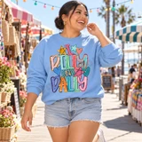 I Dilly and Dally DTF transfer in rainbow bubble lettering with hand-doodled stars and hearts in pastel and bright colors Shown on a Carolina Blue crewneck sweatshirt.