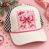 Pink Santa hat and glittery pink bow DTF transfer with black belt buckle center, stars, snowflakes, and polka-dot stripe background on a lavender shirt Shown on a ivory front panel with pink rope and black-and-white checkered mesh trucker hat.
