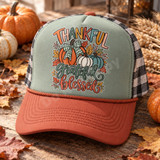 Thankful Grateful Blessed DTF transfer with hand-drawn orange, cream, and teal pumpkin trio, plaid bow, autumn leaves, and berries Shown on a sage front panel with rust bill and rope trucker hat.