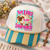 The Lord Is My Shepherd DTF transfer with pastel-swirled sheep, gold glitter-style outlines, pink bubble lettering, and Psalm 23:1 on a turquoise striped polka-dot background Shown on a Ivory foam front panel with a gold-and-teal striped bill, gold rope, white mesh back trucker hat.