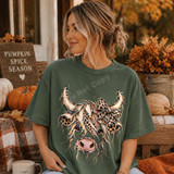 Highland cow DTF transfer with leopard print bow and frayed fabric-style patchwork texture on a sage green shirt