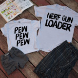 PEW PEW PEW Nerf Gun Mommy or Daddy and Me Sublimation Transfer T-Shirt Set, featuring matching T-shirts with playful text designs laid out on a rustic wooden surface with comic books nearby.