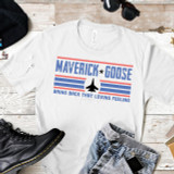 Bring Back That Loving Feeling Sublimation Transfer, sport-themed T-shirt with Maverick Goose fighter jet graphic and patriotic color scheme, laid out with accessories and jeans.