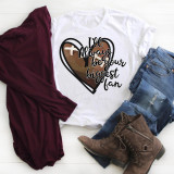 I'll always be your biggest fan Football Sublimation Transfer, white T-shirt with a heart and football graphic and inspirational message, paired with jeans, boots, and a burgundy scarf on a white wooden surface.