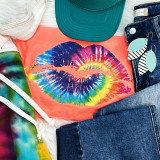 Tie Dye Lips Screen Print Heat Transfer, colorful lips print on coral-colored t-shirt with accessories like denim jeans, striped earrings, green cap, and multicolored hoodie surrounding it.
