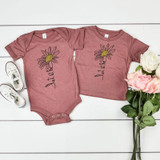 Let It Be Daisy YOUTH Screen Print Heat Transfer, two pink children's t-shirts with a daisy flower and handwritten-style text on a white wooden surface with a pair of white shoes and pink and white roses.