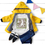 Dino collage sublimation transfer, colorful dinosaur themed design on a white T-shirt laid out with kids' clothing and accessories on white wooden surface.