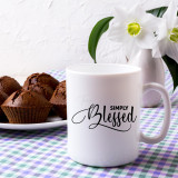 Simply Blessed Sublimation Transfer, white mug with black and cursive text print and a vase of white flowers in the background.