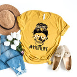 Sunflower Mom Life Skeleton FINAL STOCK Screen Print Heat Transfer, a yellow T-shirt featuring a skull with sunflower hair and the hashtag #MOMLIFE, surrounded by accessories including a straw hat, white flowers, distressed blue jeans, and beige slip-on shoes.