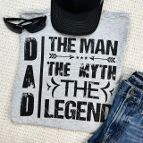 The Man The Myth The Legend DAD Screen Print Heat Transfer, a grey t-shirt with a black distressed text design, paired with sunglasses, a black cap, and blue jeans.