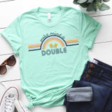 Make Mine a Double FINAL STOCK Screen Print Heat Transfer T-shirt, light green casual tee with a rainbow and beer glasses graphic, paired with sunglasses, jeans, and sneakers on white wooden background.