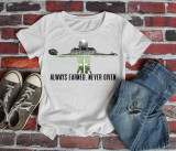 Always Earned, Never Given Sublimation Transfer T-shirt with an alien spaceship graphic and motivational quote displayed on a casual outfit with jeans and sneakers against a brick wall background.