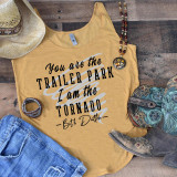 You Are The Trailer Park I Am The Tornado Screen Print Transfer, flat lay of a yellow tank top featuring the quote, with cowboy hat, jewelry, boots, jeans, and a beaded necklace around it on wooden background