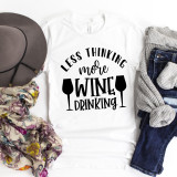 Less Thinking More Wine Drinking sublimation transfer on a white T-shirt, with additional accessories like a hat, scarf, jeans, and socks arranged around it.