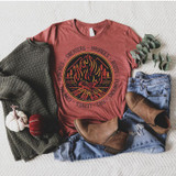 Sweaters Hayrides Boots Pumpkins Screen Print Transfer, flat lay of a fall-themed casual outfit featuring a graphic t-shirt with a bonfire and trees design, paired with denim jeans and ankle boots, surrounded by cozy sweaters, mini pumpkins, and a sprig of greenery.