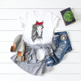 Horse Head with Bandana Sublimation Transfer, printed on a white T-shirt, showcased with casual jeans, striped shirt, gray shoes, and a small potted plant on a white wooden background.