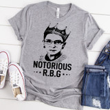 Notorious R.B.G Screen Print Transfer, graphic T-shirt with an illustrated portrait of Ruth Bader Ginsburg wearing a crown and the text 'Notorious R.B.G' on a gray shirt.