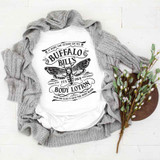 Buffalo Bill's Body Lotion Sublimation Transfer, white t-shirt with black graphic print of a moth and text, gray knitted cardigan, and a branch of green and purple eucalyptus leaves on a white wooden surface.