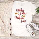 Chunky Thighs & Pumpkin Pies Sublimation Transfer on a white t-shirt, with a cozy cream knit cardigan and white sneakers with black accents, on a wooden surface with a small green plant nearby.