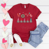 Love Gnomes ADULT Screen Print Transfer, red T-shirt with colorful gnome and love design paired with light blue jeans and white sneakers, laid out on a white wooden surface with pink and white heart decorations.