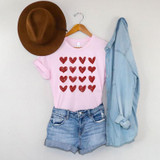 Red Hearts Metallic Screen Print Transfer, red glitter hearts design on a pink t-shirt with denim shorts, a brown hat, and a light blue denim shirt hanging on hanger.