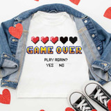 Game Over Sublimation Transfer, an image of a white t-shirt with pixelated hearts and text design, laid flat with a denim jacket and sneakers for display.