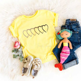 Unity Open Heart YOUTH FINAL STOCK Screen Print Heat Transfer, yellow T-shirt with heart outline print, denim jeans, plush mermaid toy, baby shoes, and pink rose on a plush white background.