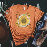 Free Spirit And Kind Soul Screen Print Transfer T-shirt in orange featuring a sunflower design with butterflies and the phrase "Free Spirit And Kind Soul" on a black patterned background.