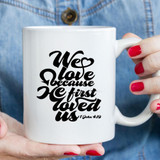 We Love Because Sublimation Transfer, a white ceramic mug with black printed text of a heartfelt Bible verse from 1 John 4:19.