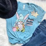 Happy Easter Gnomies Screen Print Heat Transfer, a cartoon gnome with bunny ears holding a carrot and a pink bunny pom-pom, on a light blue t-shirt with text.