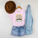 Got That Sunshine In My Pocket Screen Print Heat Transfer T-Shirt, pink casual t-shirt with mountain and sunrise graphic design, paired with denim shorts and a light blue denim shirt, brown wide-brim hat hanging on a hanger on a white background.