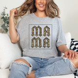 Leopard Print MAMA Screen Print Heat Transfer, a woman wearing a grey t-shirt featuring a bold leopard print MAMA design, sitting on a white couch with distressed jeans.