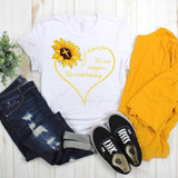 Jesus It's Not Religion It's A Relationship Sublimation Transfer, a white T-shirt with a sunflower and cross design, paired with distressed jeans, black Vans sneakers, a yellow jacket, and a small plant on a wooden surface.