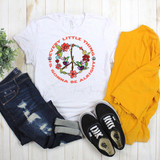 Peace Sign Hummingbirds Every Little Thing Is Gonna Be Alright Bob Marley Sublimation Transfer T-shirt, featuring a colorful peace sign with hummingbirds and floral designs, laid flat with jeans, yellow pants, and black Vans shoes beside it.