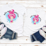 Salty Hair Don't Care Mermaid Summer Sublimation Transfer, pair of white T-shirts with pink-haired mermaid design and the text 'Salty Hair Don't Care', laid flat with sneakers and denim shorts on a white wooden surface