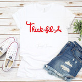 Thick-Fil-A Sublimation Transfer, white T-shirt with red logo on a wooden surface alongside sneakers, denim shorts, and green plant.