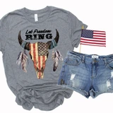 Patriotic Skull Screen Print Heat Transfer, gray t-shirt with American flag skull and feathers design, distressed denim shorts, small American flag, and patriotic themed clothing items.
