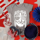 Have a Willie Nice Day INFANT Screen Print Heat Transfer on a gray baby onesie, displayed among patriotic-themed decorations and accessories.