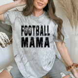 Football Mama Distressed BLACK DTF Heat Transfer, close-up of a woman wearing a casual grey t-shirt with a distressed black 'Football Mama' print, sitting on a neutral-toned background.