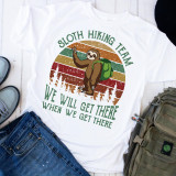 Sloth Hiking Team Sublimation Transfer T-shirt, featuring a cheerful sloth with a green backpack and hiking gear, posing in front of a retro striped background with trees and an inspiring outdoor message.