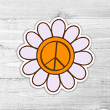 Orange Peace Sign Flower Retro Die Cut Sticker, colorful sticker featuring a peace sign in the center of a flower with white petals on a wooden background.