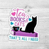 Tea, Books & Cats That's All I Need Die Cut Sticker, featuring a black cat, a coffee mug, books, and colorful hearts on a white wooden background.