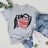 Product Straight Outta Hawkins DTF Transfer, graphic T-shirt with an illustration of an apple and the text "Straight Outta Hawkins" in red and black, laid flat with denim jeans and white sneakers, on a textured white background with a green leafy branch.