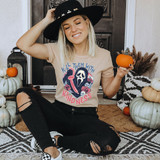 Kill Them With Kindness DTF Transfer, woman wearing a graphic t-shirt with the phrase 'Kill Them With Kindness' and a spooky skull design, sitting among pumpkins and fall decorations.