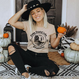 Camp Crystal Lake Counselor DTF Transfer, woman wearing a beige t-shirt with the Camp Crystal Lake Counselor logo and holding small pumpkins, sitting on a cozy rug with fall decor around.