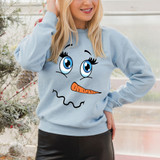 Snowman Face DTF Transfer, cartoon snowman face with large blue eyes, orange carrot nose, and playful expression printed on a light blue sweatshirt.